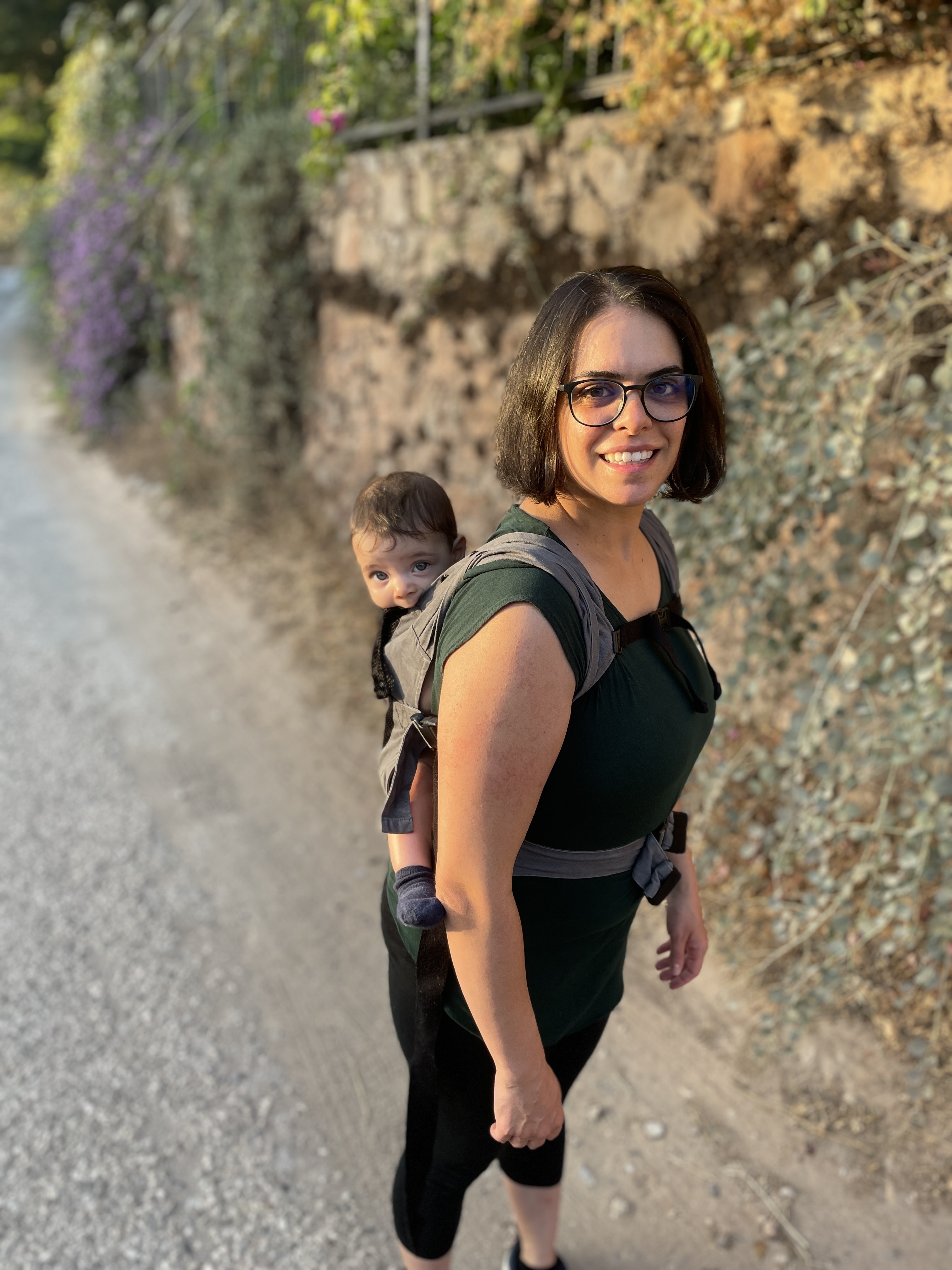 May Naimi-Jones carrying a baby in a sling on the back.